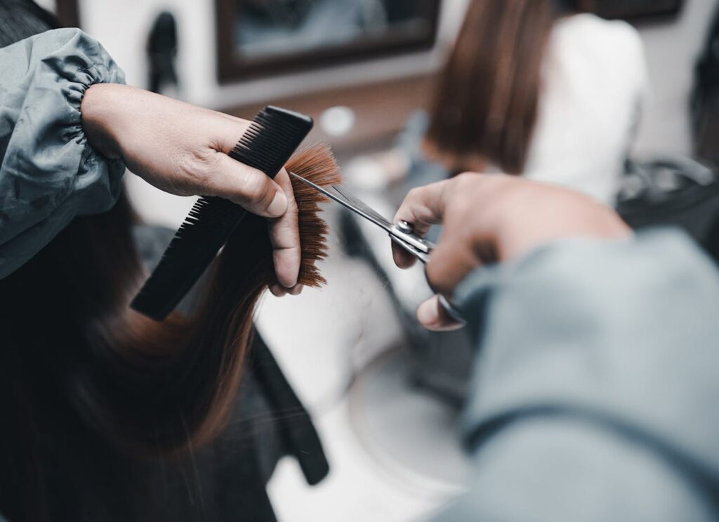 Close-up of a hairdresser cutting hair with scissors in a salon, highlighting expert technique and style.