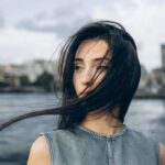 A young woman with flowing hair stands by the Bosphorus in Istanbul, Türkiye.
