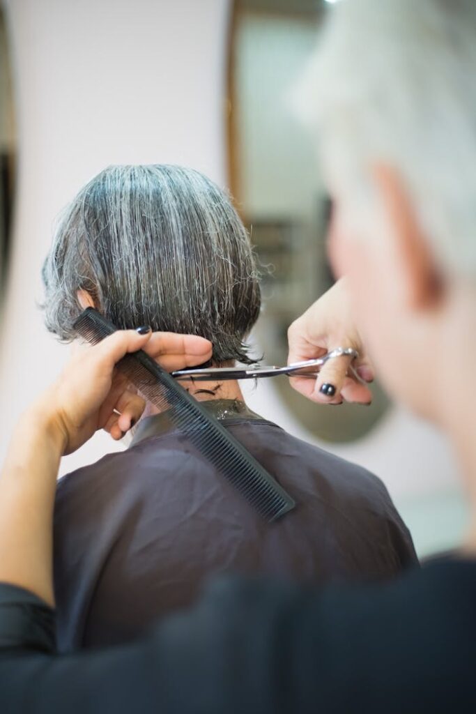 A hairstylist skillfully cutting a woman's hair with scissors and comb indoors.